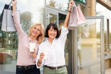 Two mature women having fun while doing shopping and drinking coffee. Pastime concept of mature peopleの写真素材