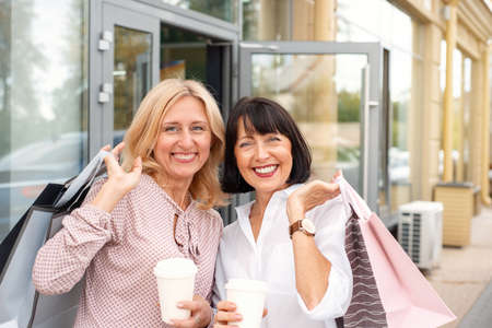 Two mature women having fun while doing shopping and drinking coffee. Pastime concept of mature peopleの写真素材