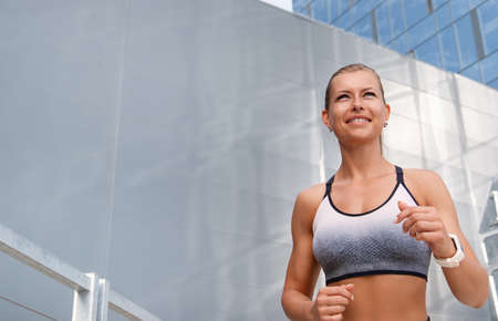 Happy fitness sporty woman running early in the morning city at sunrise. Healthy lifestyle concept.の写真素材