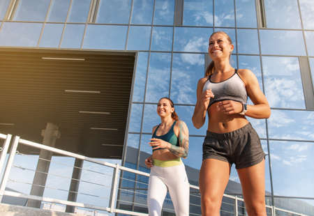Two women exercising by jogging in the city while sun is setting. Healthy lifestyle concept.の写真素材