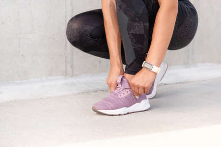 Close up shoot of woman's hands tying the shoelaces of sporty sneakers. Fitness sporty woman is preparing for running. Healthy lifestyle concept.の写真素材