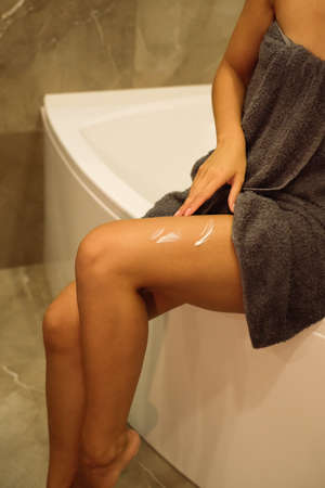 Shoot of woman's legs with a cosmetic cream. Skin care products. Woman moisturize her body skin. Beauty spa concept.の写真素材