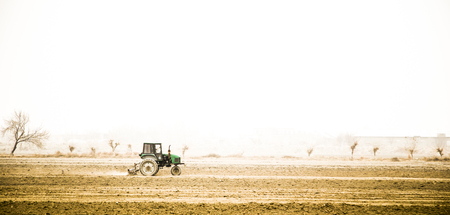 Farmer in old tractor preparing land with seedbed cultivator