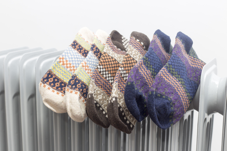 oil heater drying three pair of colourful socks on white background