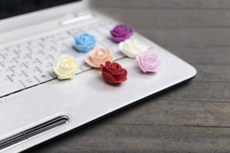 Valentine's day concept, laptop, colourful roses on gray wooden background