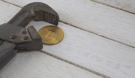 Bitcoin in the clamp. Risk of economic crisis.On white wooden background.の写真素材