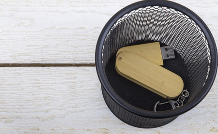 wooden flash drive in trash can on white background.の写真素材