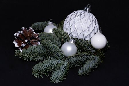 Art installation on a black background for New Year or Christmas from spruce twigs, glass balls and pine cone.の写真素材