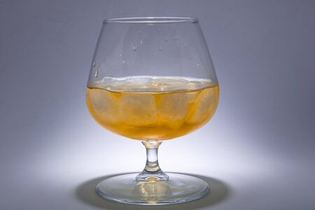A glass of whiskey and ice. Art installation with lighting from above and close-up.の写真素材