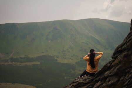 girl sitting on rock and fixing her hair