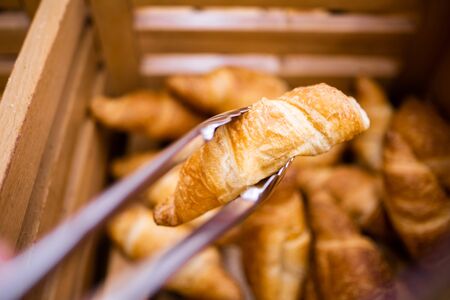 Fresh french croissants man takes for breakfast with tongsの写真素材