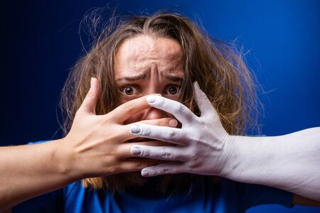 Hands of different colors cover the girls mouth. A girl with disheveled hair is afraid and cannot say anythingの写真素材