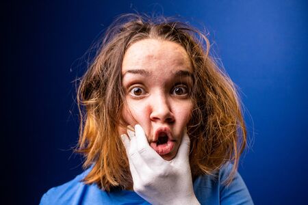 A hand makes a young girl speak. Girl with tousled hair under the pressure of surrounding people