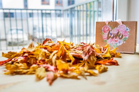 Autumn love concept. Dry autumn leaves on a table with a paper bagの写真素材