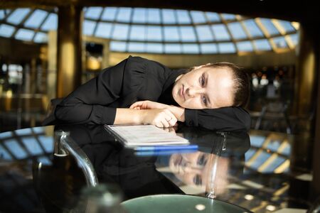 Business girl in black lay on the table, looking thoughtfully into the voidの写真素材