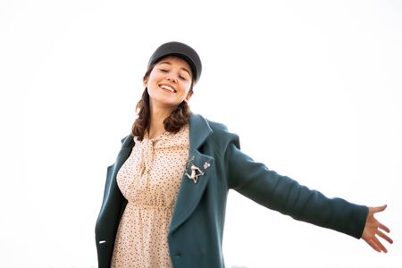 A beautiful happy batwoman sincerely smiles, eyes wide open and arms spread apart. Girl in warm clothes isolated on white backgroundの写真素材