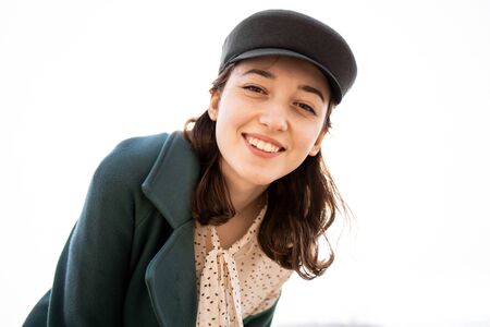 Beautiful happy girl sincerely smiles, looking at the camera on a white background. Girl in warm clothes isolated on white backgroundの写真素材
