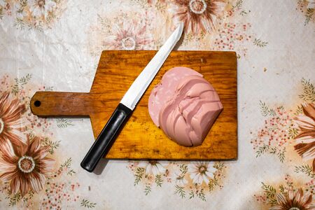 Sliced sausage on a wooden cutting board. Cutting on an old rustic table. View from aboveの写真素材