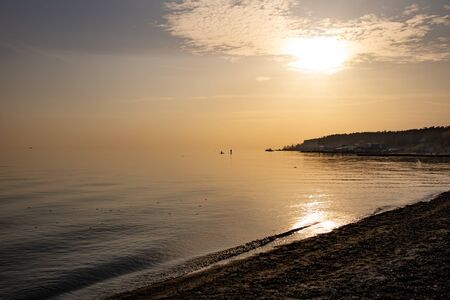 Sunset by the sea. The calm water of the sea. Fishermen in the distance at seaの写真素材