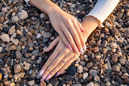 Beautiful manicure on female hands on a background of small stones
