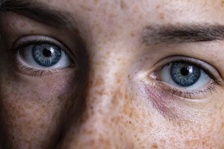 Face of a girl with freckles. Blue eyes of a girl close-upの写真素材