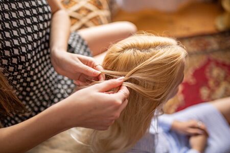 woman braids braids to a young girl. Female hands weave braidsの写真素材