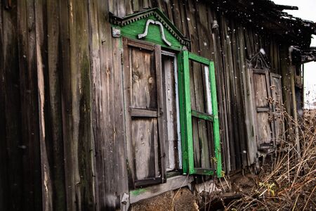 broken windows of an old wooden house in snowfall. Windows of a country house with broken glassの写真素材