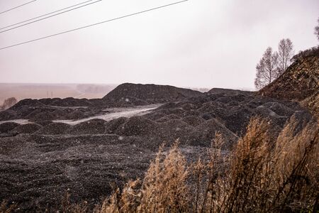 mountains of small black stones against a cloudy sky in autumnの写真素材
