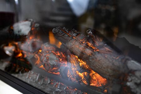 red charred wood in the fireplace. Smouldering coals in the home fireplace