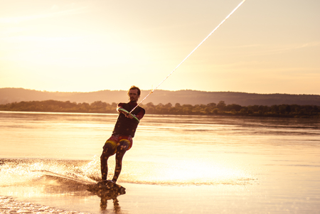 Wakeboarding. Athlete silhouette with splash of water during sunsetの写真素材