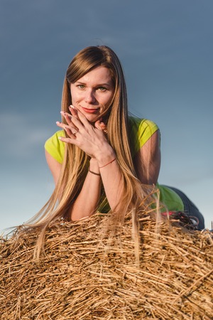 Young woman outdoors in a wheat field on sunny autumn day