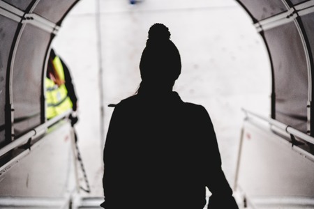 Silhouette of a woman in front of bright light in the airportの写真素材
