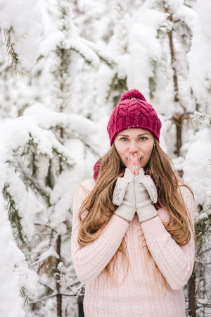 Smiling young woman outdoors in a winter forest covered with a fresh snow