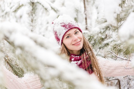 Smiling young woman outdoors in a winter forest covered with a fresh snowの写真素材