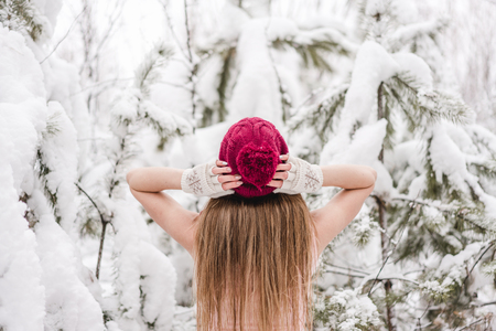 Smiling young woman outdoors in a winter forest covered with a fresh snowの写真素材