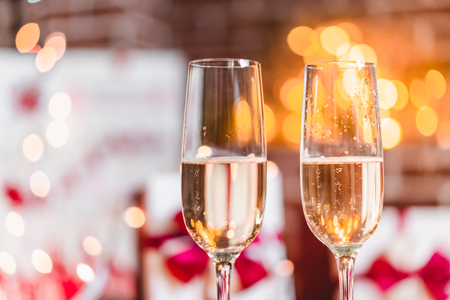 Two champagne glasses in front of christmas presents and sparkling backgroundの写真素材