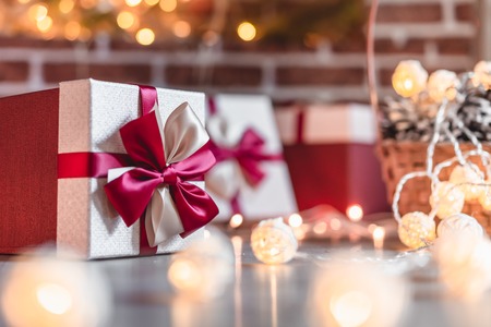 Wrapped gift with red ribbon on fireplace background at home.の写真素材