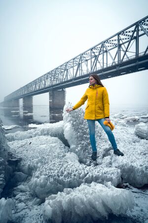 Young woman in yellow jacket and blue jeans standing on iceの写真素材