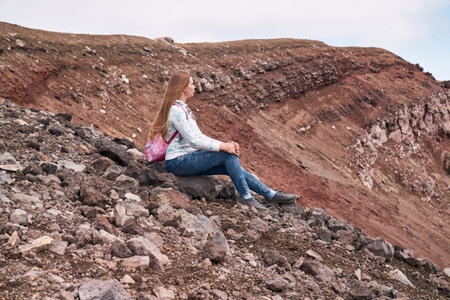 Young woman hiking to the top of the volcano. Kamchatka peninsula, Russia