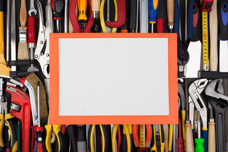A decorative white page with small inclusions texture, on a background of lined up work tools 