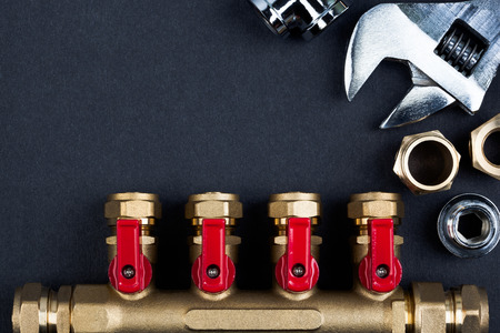 Brass manifold valve and wrench on textured dark background.の写真素材