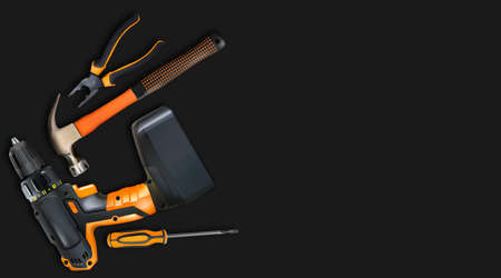 Orange tools professional realistic on black background. Hammer, cordless drill, screwdriver and...