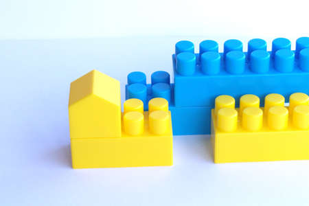 Small house made of children's designer color Ukraine Flag, white background with copy space. Construction and restoration. Bright multicolored details toy. Banner. Concept of a new home for family.の写真素材