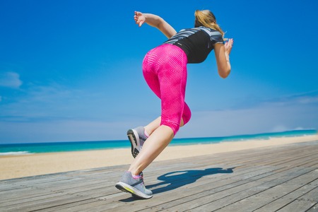 Female athlete in starting position ready for running. Young woman ready for sports exercise on beach. Sporty woman . Healhty lifestyle.の写真素材
