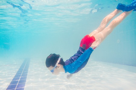 Underwater Young Boy Fun in the Swimming Pool with Goggles. Summer Vacation Fun.の写真素材