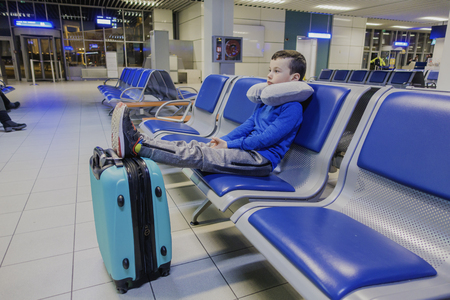 Young boy sitting alone in a corridor of airport at feeling sad mood.の写真素材