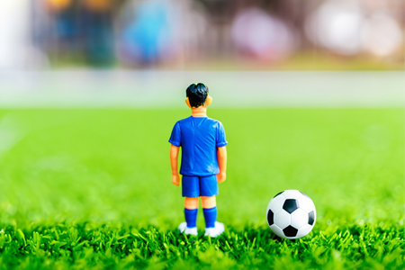 A small figurine of a boy standing next to a soccer ball, closeup portrait shot, tilt shift focus.の素材