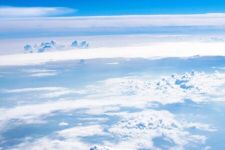 Aerial view of the blue skies and horizon with fluffy clouds and the earth below