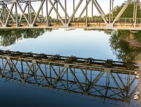 Reflection of the railway bridge in the river at sunset in the summer.の写真素材