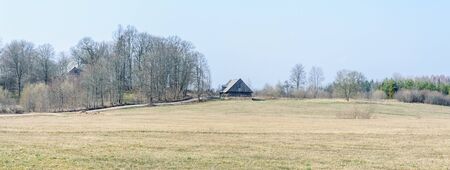 An old barn by a road in the countryside in early spring when the trees are still without leavesの写真素材